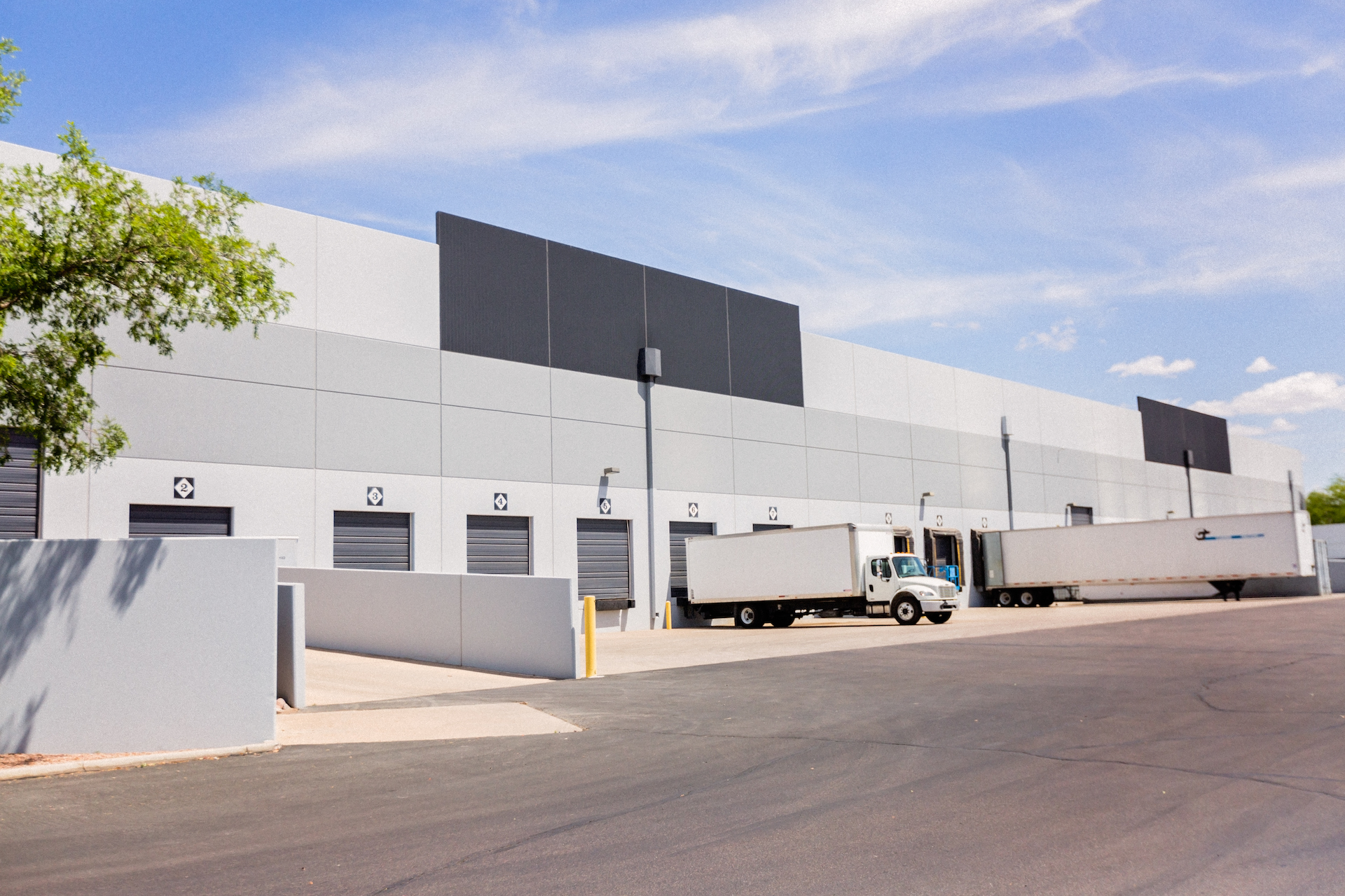 Trucks backed into the loading docks of SKU Distribution's warehouse under a blue sky