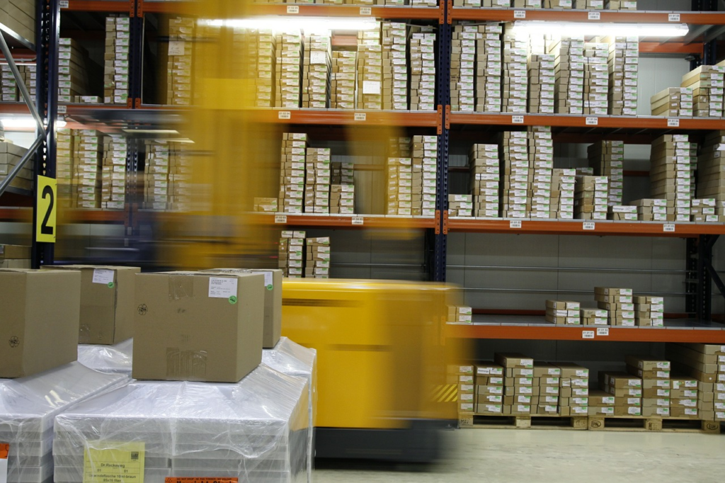Forklift moving wrapped pallets in a warehouse